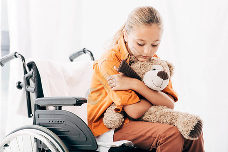 抱着泰迪熊坐在轮椅上的沉思孩子图片