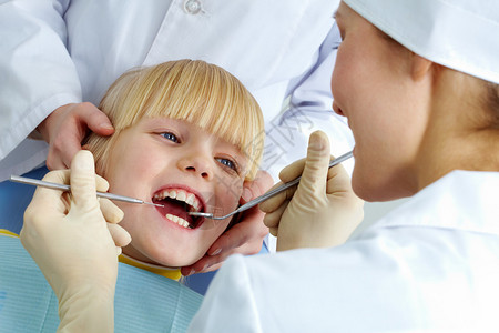 由医生和助理检查其牙齿的小女孩图片