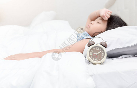 床上的闹钟生病的孩子躺着头痛图片