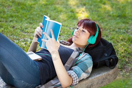 女孩躺在长凳上法律书戴着耳机听音乐图片