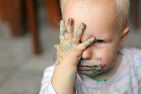 一个小孩女涂满了乱涂的油漆手遮住背景图片