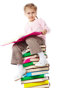 一个小女孩带着一本书坐在堆高清图片
