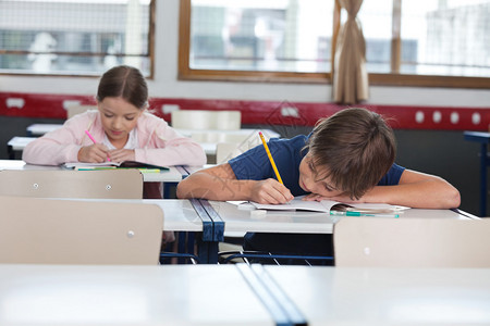 小学男孩和女孩在教室的办公桌前学习图片