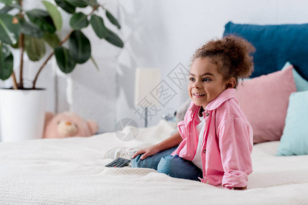 坐在床上看电视秀的非裔美国人儿童笑着在床图片