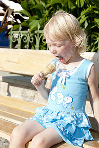坐在长凳上吃冰淇淋的小女孩图片