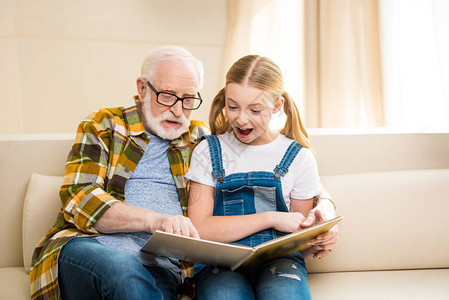 快乐的祖父和孙女在家一起看书图片