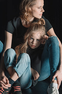 女儿和母亲坐在地上被隔绝在黑图片