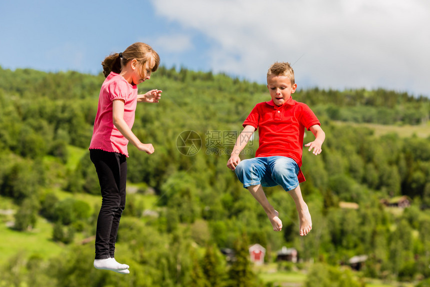 两名扫描儿童在跳上大型可充气滚动蹦床时玩图片