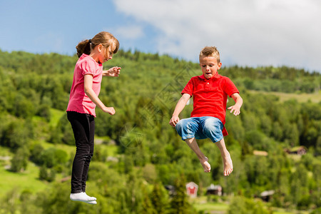 两名扫描儿童在跳上大型可充气滚动蹦床时玩图片