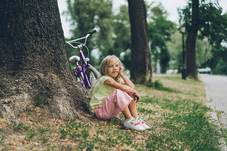 可爱的孩子在公园树下自行车旁图片