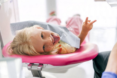 儿童在牙医办公室插舌头和展示和平标图片