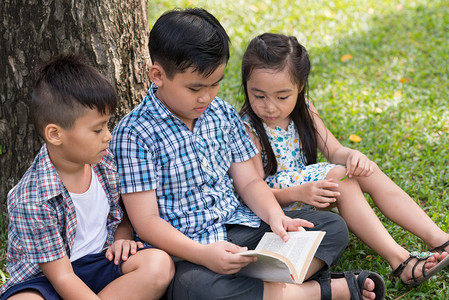 亚洲小孩在公园里一起读书图片