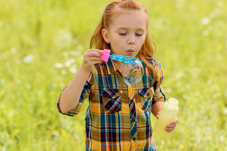 孩子在草地上吹肥皂泡的肖像图片