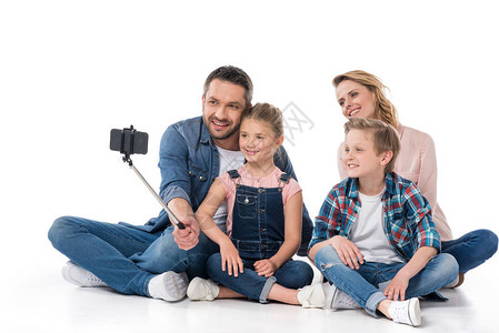 家庭笑着用智能手机自拍而坐在地图片
