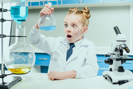穿着白大衣的女中学生在化学实验室实验试剂图片