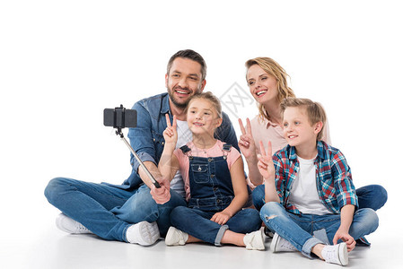 家庭快乐用智能手机自拍同时展示白色孤图片
