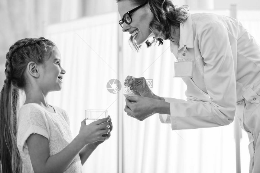 笑的医生给小女孩提供药品的侧面景图片