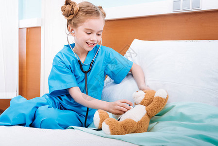 微笑的女孩护士Teddy熊的心跳用听诊器倾听Ted图片