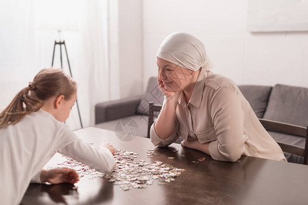可爱的小孩生病的祖母在手帕上玩拼图片