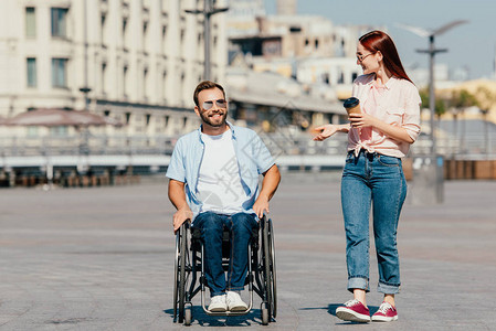 坐在轮椅上笑着微笑的帅男友和有咖啡去街上图片