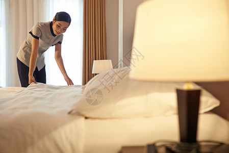 年轻美女在酒店房间安排床上睡觉换床布图片
