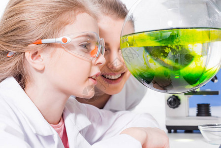 在化学实验室中微笑的教师和学生在用试剂检查瓶图片
