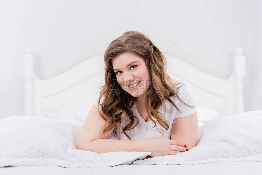 笑着的年轻女人躺在床上看着家里的图片