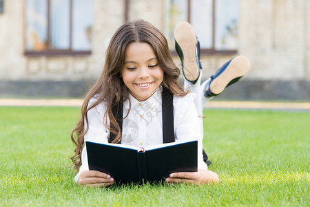 基础教育可爱的小女孩学习阅读女学生校服躺在草坪上图片