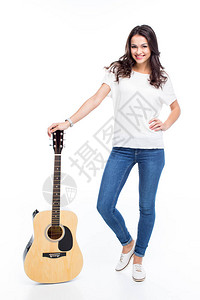 美丽的年轻女子站在吉他上对着被白色隔图片