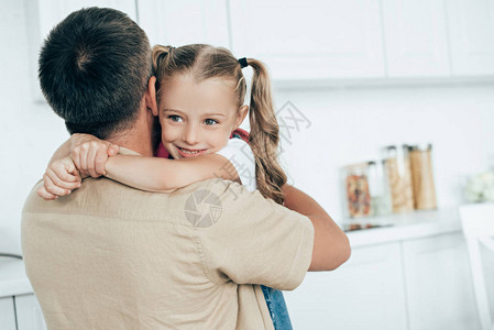 父亲和微笑的女儿背着包拥抱对方在里图片