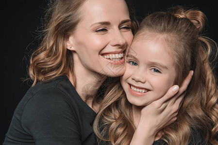 时髦的女儿和母亲微笑与拥抱的肖像图片