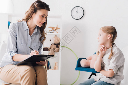 成人心理学家有剪贴板坐在小孩子面图片