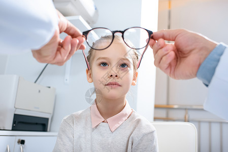 眼科医生在诊所对青春期前儿童戴新眼镜的图片