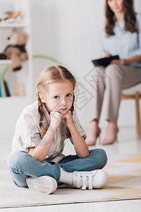 沮丧的小孩坐在地板上看着相机背景模图片