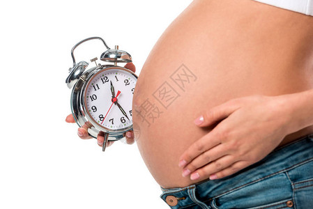 孕妇在腹部附近抓着闹钟时的部分图片