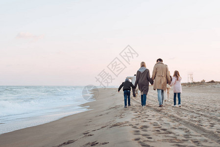 一家人手牵走在沙滩上散步图片