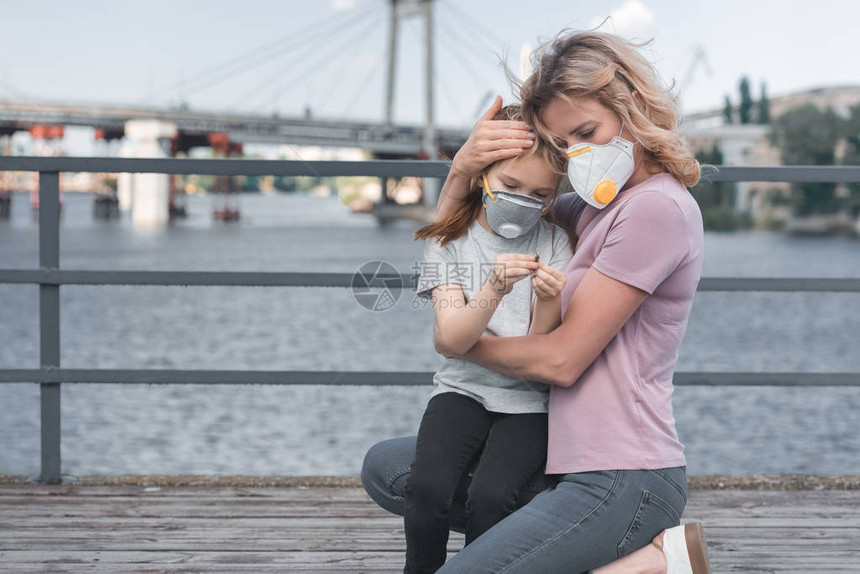 母亲戴着保护面罩抱在桥上的女儿空气污图片