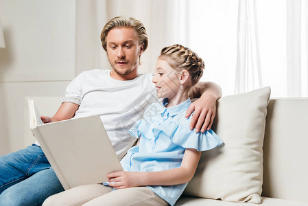 金发父亲和女儿在家沙发上图片