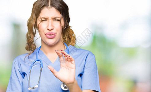 身穿医疗制服的年轻成年女医生厌恶的表情图片