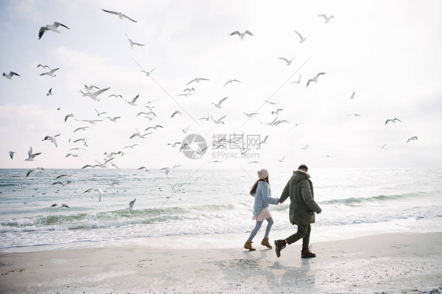 年轻夫妇手牵在冬季的海滨上图片