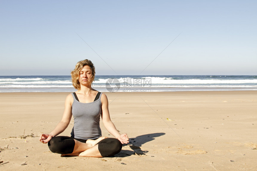 年轻健康的女人在沙滩上冥想图片