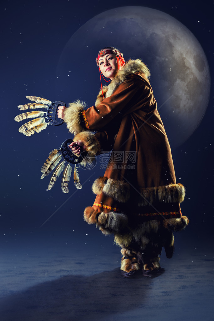 美丽的年轻女孩在寒雪夜晚背景下跳着北部小民族传统服装的礼仪舞图片