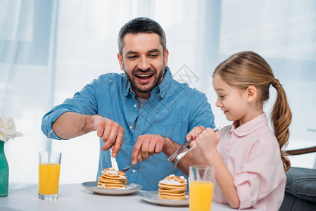 快乐的父亲和小女儿在家吃早饭开心的图片