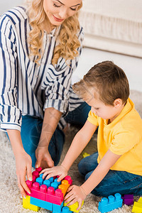母亲和小儿子在家里的地板上一起玩具时图片