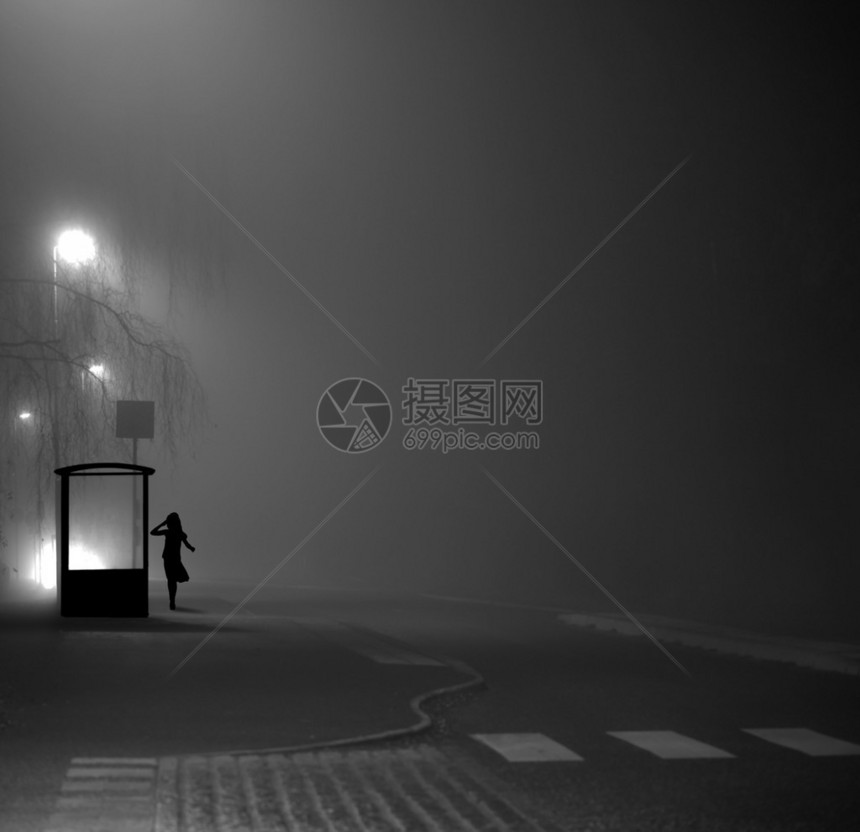 在深雾夜由避难所等候公共汽车的年轻图片