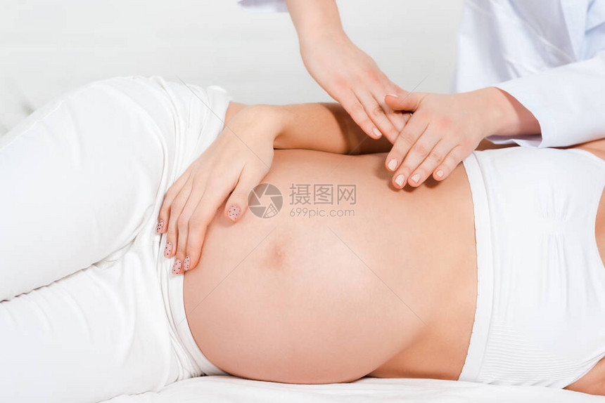 按摩桌上对怀孕女孩进行腹部按摩的按摩图片