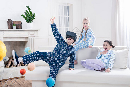 穿着睡衣的兴奋儿童在家里玩虚拟图片