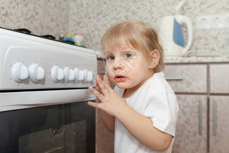 一个孩子在厨房里玩烤箱图片