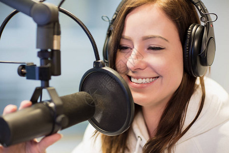 在电台演播室使用耳机和麦克风时微笑的图片