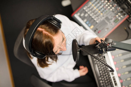 在电台演播室使用麦克风和耳机的女骑手图片